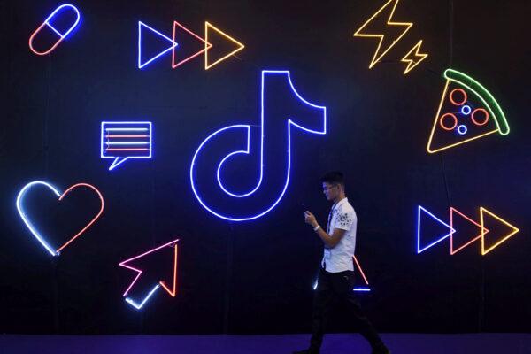 A man holding a phone walks past a sign for Chinese company ByteDance's app TikTok, known locally as Douyin, at the International Artificial Products Expo in Hangzhou, Zhejiang Province, China, on Oct. 18, 2019. (STR/Files/Reuters)