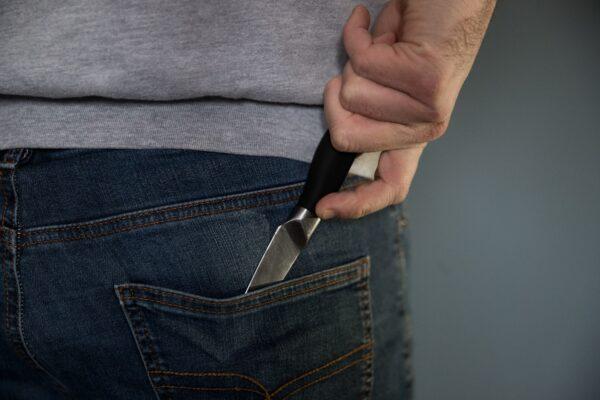 A man pulls a knife from his back pocket in a file photo dated Jan. 16, 2020. (Andrew Matthews/PA)