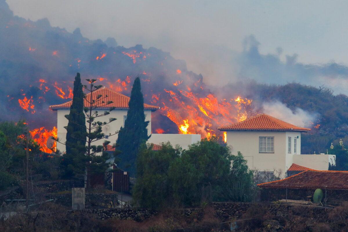 Lava flows behind houses following the eruption of a volcano in the Cumbre Vieja national park at Los Llanos de Aridane, on the Canary Island of La Palma, on Sept. 20, 2021. (Borja Suarez/Reuters)