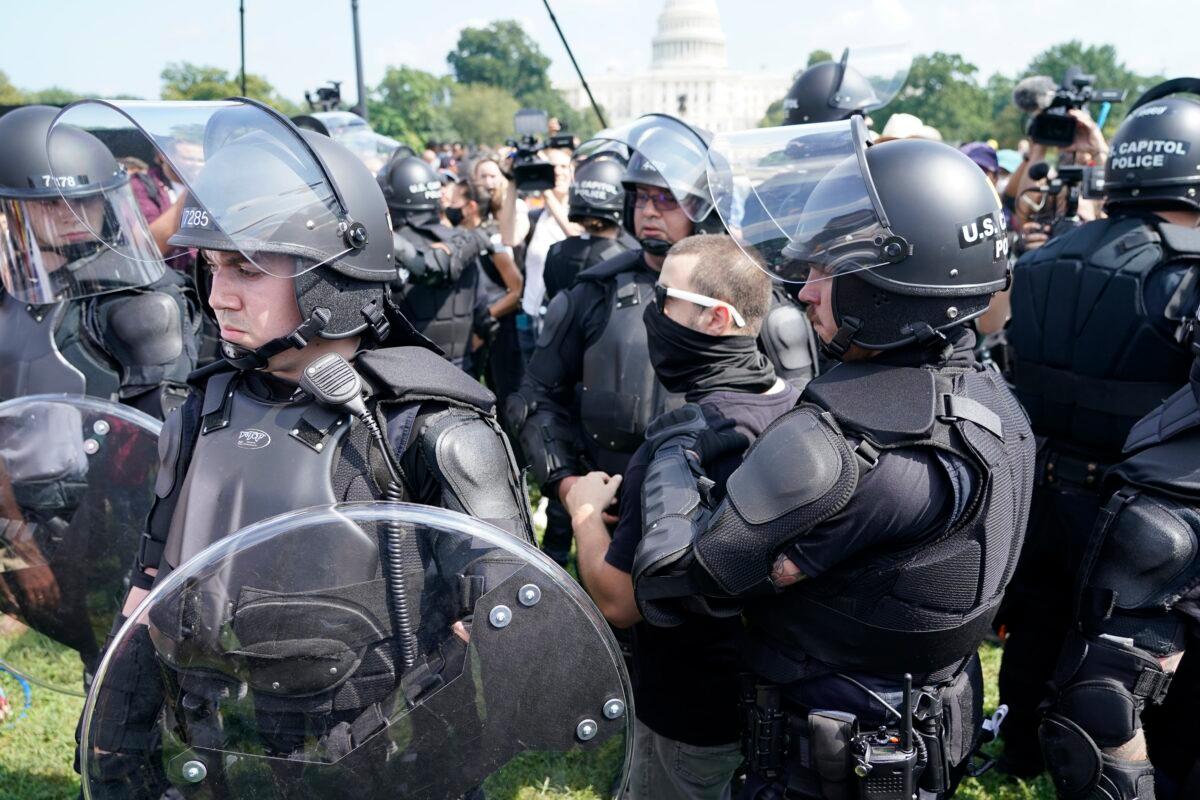 Police circle a man, center with glasses, during a rally near the U.S. Capitol in Washington on Sept. 18, 2021. (Gemunu Amarasinghe/AP Photo)