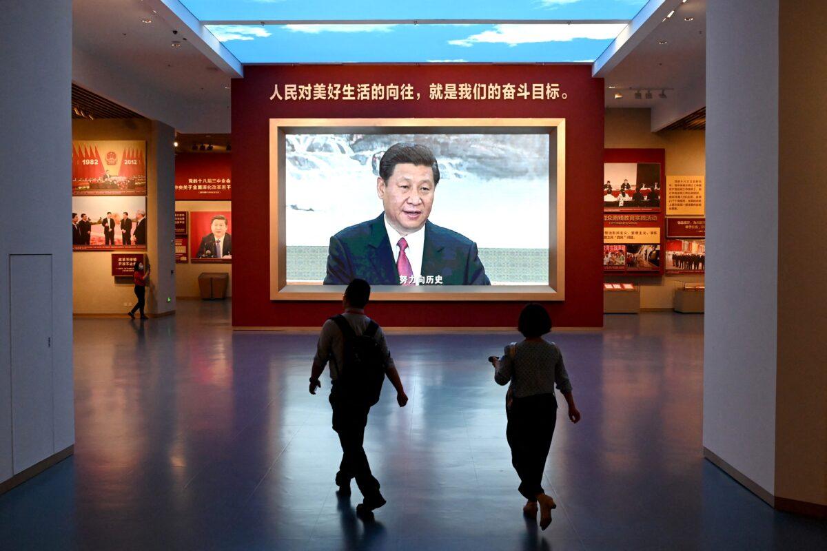 Journalists walk past a screen showing video footage of Chinese President Xi Jinping, during a visit to the Museum of the Communist Party of China, near the Birds Nest national stadium in Beijing on June 25, 2021. (Noel Celis/AFP via Getty Images)