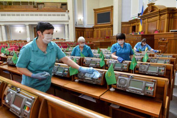 Employees use disinfectant while cleaning the Ukrainian lawmakers' working places in the session hall of parliament in Kiev, Ukraine, on March 19, 2020. (Stringer/Reuters photo)