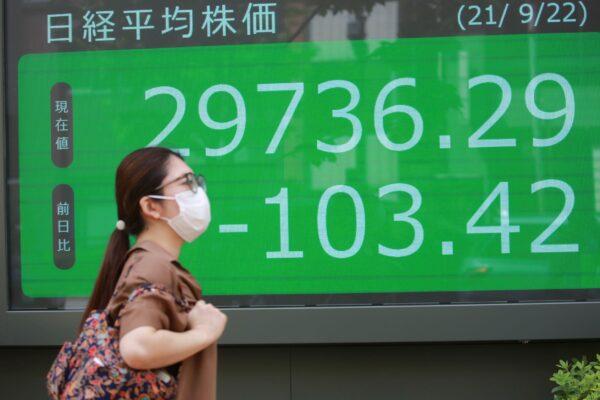 A woman walks by an electronic stock board of a securities firm in Tokyo, Japan on Sept. 22, 2021. (Koji Sasahara/AP Photo)