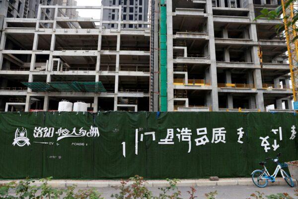 A peeling Evergrande Oasis logo for a housing complex developed by Evergrande Group, is seen outside the construction site where the residential buildings stand unfinished, in Luoyang, China on September 16, 2021. (Carlos Garcia Rawlins/Reuters)