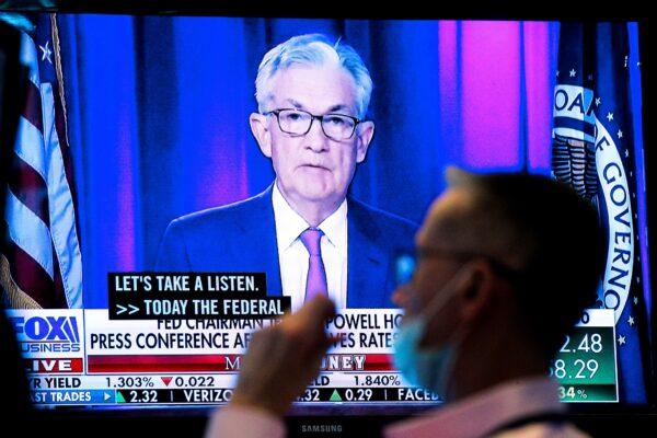 A screen displays a statement by Federal Reserve Chair Jerome Powell following the Federal Reserve's announcement as a trader works on the trading floor of the New York Stock Exchange (NYSE) on Sept. 22, 2021. (Brendan McDermid/Reuters)