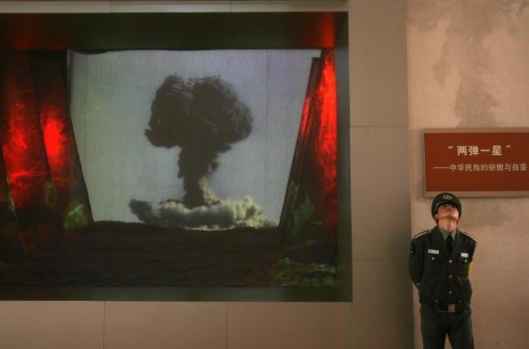 A security guard stands beside a screen showing video about China's atomic bomb and hydrogen bomb research during "Road of Revival" Exhibition at the Military Museum in Beijing, China, on Oct. 17, 2007. The exhibition displayed cultural relics, pictures, and documents featuring important historical events in China since 1840, when the nation was defeated in the Opium War. (China Photos/Getty Images)