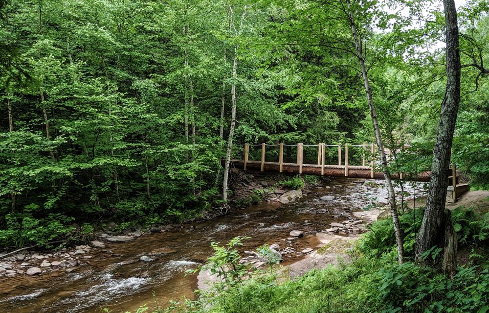 A wooden bridge stands over a rushing river. (Marissa English/Shutterstock)