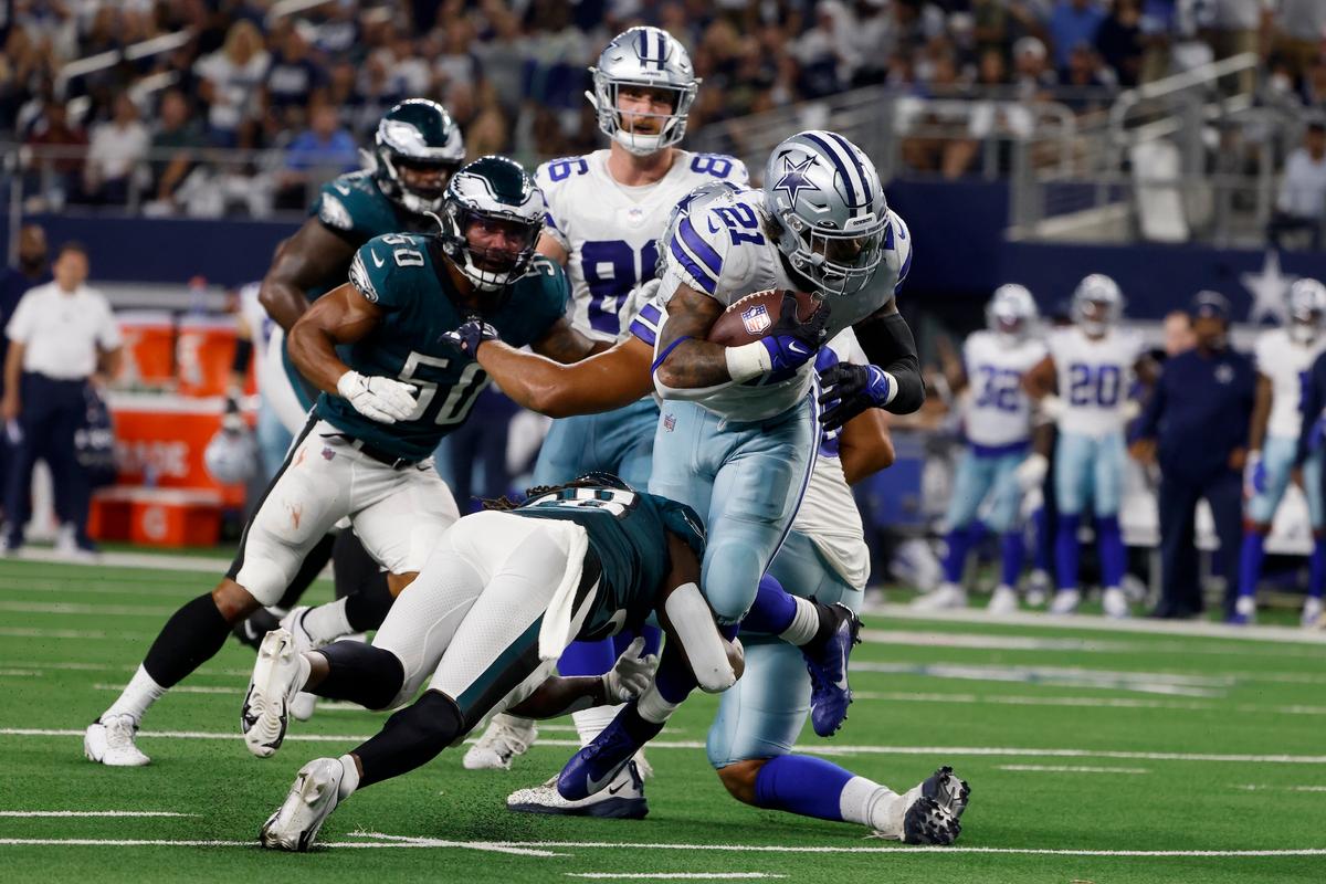Dallas Cowboys running back Ezekiel Elliott (21) breaks a tackle attempt by Philadelphia Eagles safety Anthony Harris (Bottom L), as he sprints to the end zone for a touchdown in the first half of an NFL football game in Arlington, Texas, Monday, Sept. 27, 2021. (Michael Ainsworth/AP Photo)