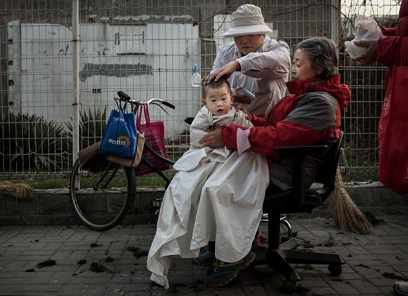 A Chinese barber cuts a child's hair in the street on November 28, 2014, in Beijing, China. While China has one of the most rapidly growing economies in the world, income inequality is still a major challenge as a large portion of the country's population lives below the national poverty level. (Kevin Frayer/Getty Images)