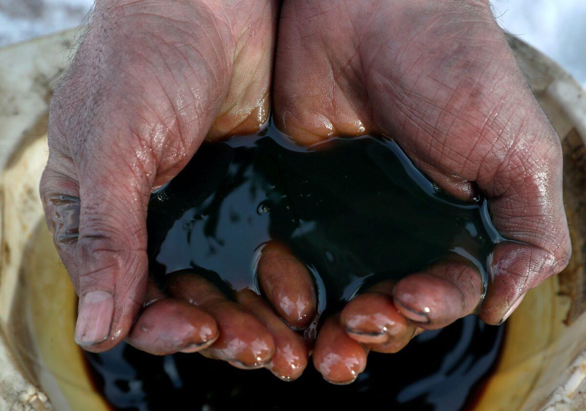 An employee holds a sample of crude oil at the Yarakta oilfield, owned by Irkutsk Oil Co, in the Irkutsk region, Russia, on March 11, 2019. (Vasily Fedosenko/Reuters)