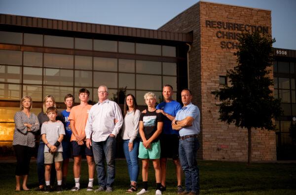 (L-R) Resurrection Christian School parents and students Vicki Sutter, Christy Fagerlin, sixth grader Lincoln Fagerlin, 11, freshman Graham Riggs, 13, junior Charlie Riggs, 16, Mike Riggs, Karen Riggs, sophomore Zach Coet, 15, Eric Coet and school board president Mark Siffring stand for a portrait outside the school on in Loveland, Colo., on Sept. 27, 2021. The group is protesting action by the state of Colorado that would shut down the private school if it doesn’t implement mask requirements. (Michael Ciaglo for the Epoch Times)