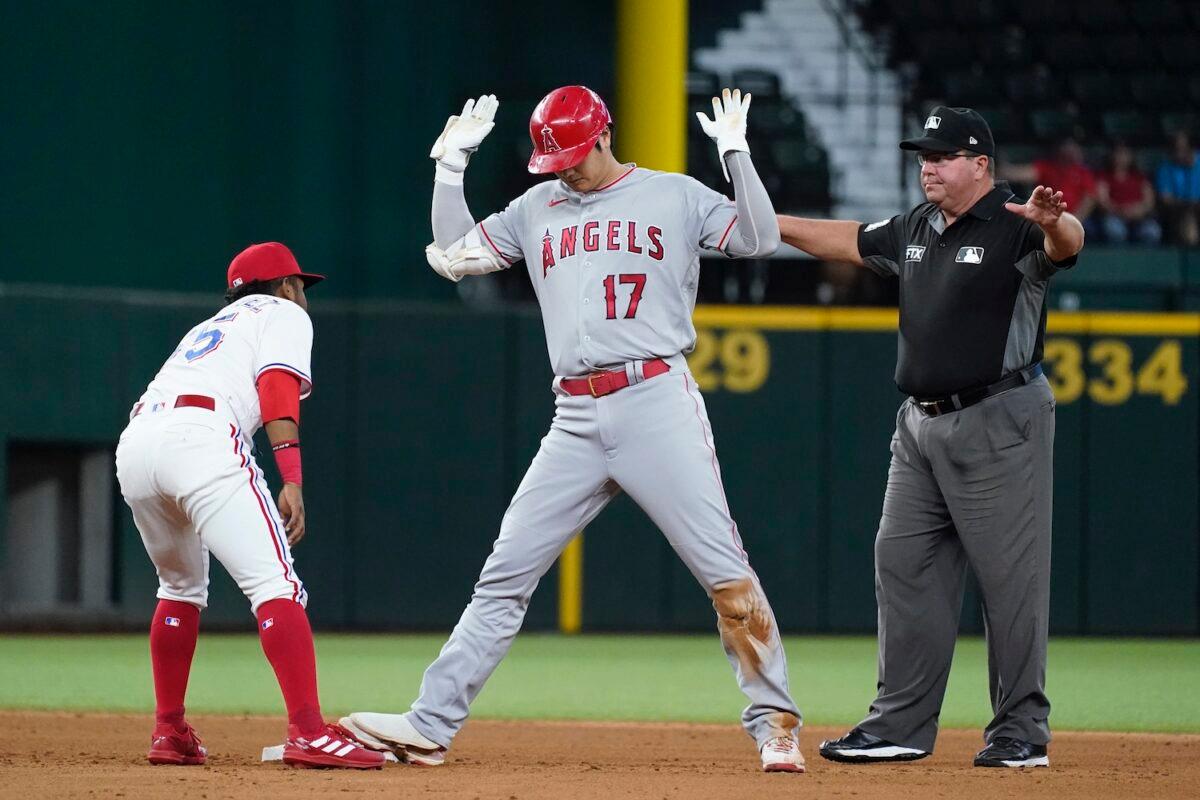 Texas Rangers shortstop Yonny Hernandez, left, stands by the bag looking at Los Angeles Angels' Shohei Ohtani (17) who reached second with a double as umpire Sam Holbrook looks on in the sixth inning of a baseball game in Arlington, Texas on Sept. 30, 2021. (AP Photo/Tony Gutierrez)