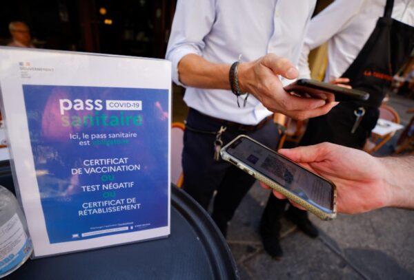A man shows his COVID-19 health pass at a restaurant as France brings on tougher restrictions required to access most public spaces and to travel by inter-city train, in Nice, France, on Aug. 9, 2021. (Eric Gaillard/Reuters)
