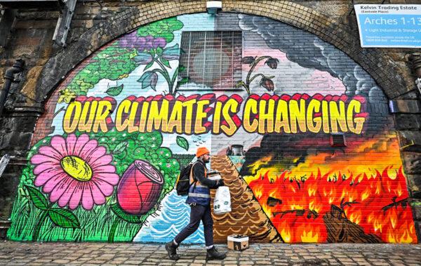 Artists paint a mural on a wall next to the Clydeside Expressway near Scottish Events Center (SEC), which will be hosting the COP26 U.N. Climate Summit in Glasgow, Scotland, on Oct. 13, 2021. (Jeff J Mitchell/Getty Images)