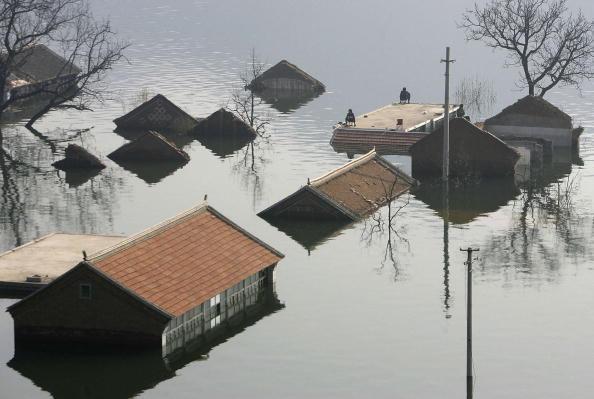 Tourists fish on a roof of a submerged house at the Huanxiu Lake, in Jixian County of Tianjin Municipality, China, on Oct. 1, 2006. (China Photos/Getty Images)
