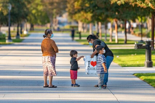 A family walks in a park after receiving free children's books from the Westminster Library in Westminster, Calif., on Sept. 22, 2020. (John Fredricks/The Epoch Times)