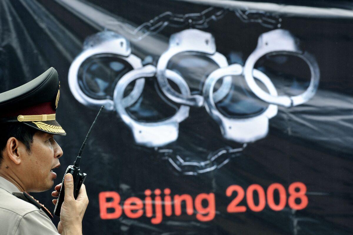 A police officer communicates over his radio standing beside an anti-Chinese banner during a demonstration by pro-Tibet activists and supporters near the venue of the Indonesian leg of the 2008 Beijing Olympic torch relay in Jakarta on April 22, 2008. (Jewel Samad/AFP via Getty Images)
