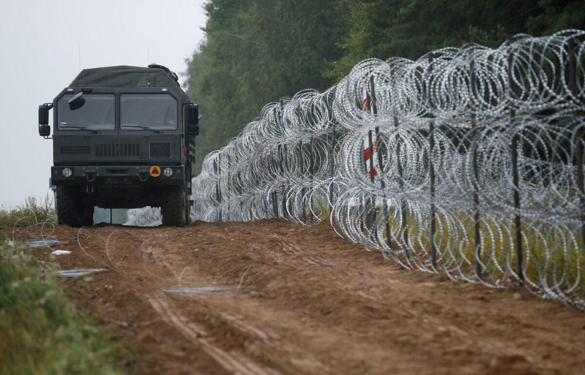 A vehicle next to a fence built by Polish soldiers on the border between Poland and Belarus near the village of Nomiki, Poland, on Aug. 26, 2021. (Kacper Pempel/Reuters)