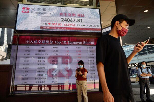 People walk past a bank's electronic board showing the Hong Kong share index at Hong Kong Stock Exchange in Hong Kong on Oct. 4, 2021. (Vincent Yu/AP Photo)