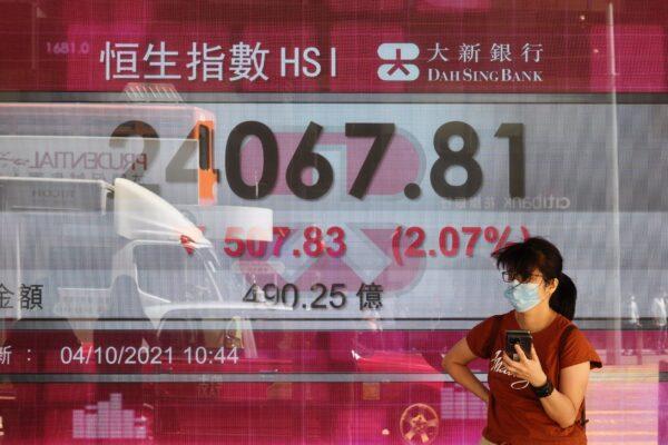 A woman walks past a bank's electronic board showing the Hong Kong share index at Hong Kong Stock Exchange in Hong Kong on Oct. 4, 2021. (Vincent Yu/AP Photo)