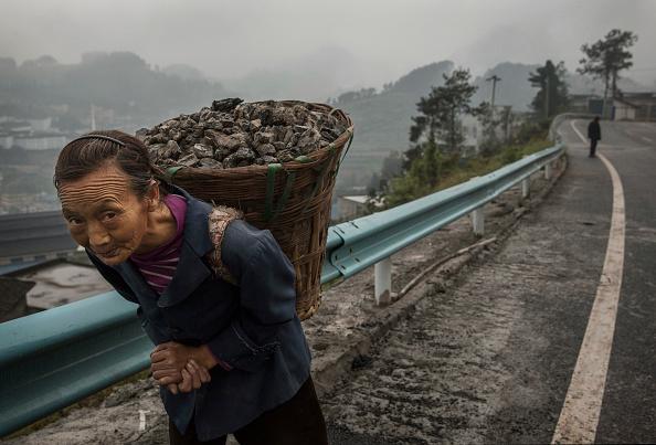 A Chinese woman carries coal in the hills above the Chishui River, in Maotai, Guizhou province, China, on Sept. 21, 2016. (Kevin Frayer/Getty Images)