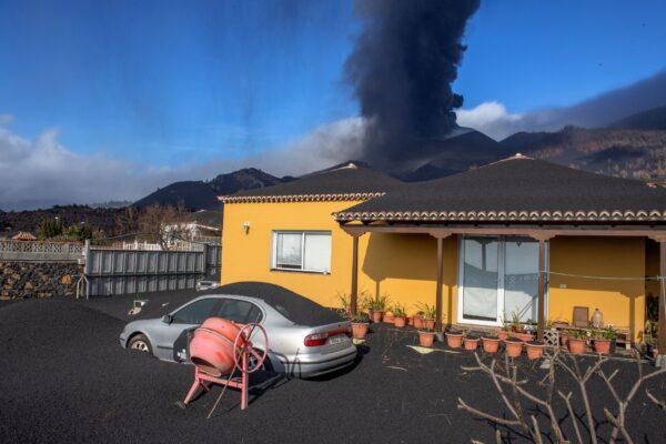 Ash covers a house, car, and garden as in the background a volcano erupts on the Canary island of La Palma, Spain, on Oct. 4, 2021. (Saul Santos/AP Photo)