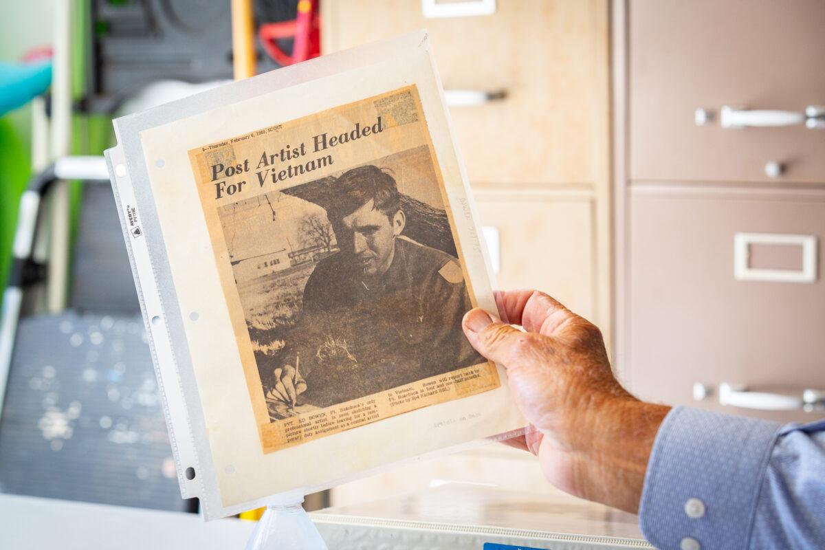 Combat artist Ed Bowen shows an article written about him in The Daily Pilot in 1969, in Newport Beach, Calif., on Sept. 14, 2021. (John Fredricks/The Epoch Times)