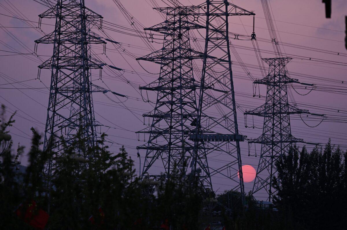 The sun sets behind electricity power pylons in Beijing on Sept. 28, 2021. (Leo Ramirez/AFP via Getty Images)