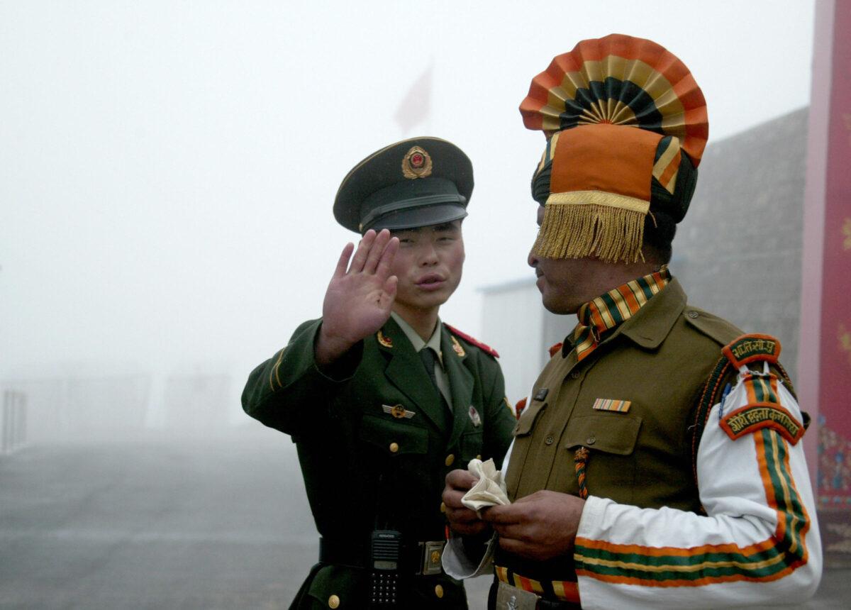 A Chinese soldier gestures as he stands near an Indian soldier on the Chinese side of the ancient Nathu La border crossing between India and China on July 10, 2008. (Diptendu Dutta/AFP via Getty Images)