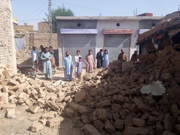 Residents gather near the rubble of a damaged house following an earthquake in Harnai, Balochistan, Pakistan, on Oct. 7, 2021. (Naseer Ahmed/Reuters)