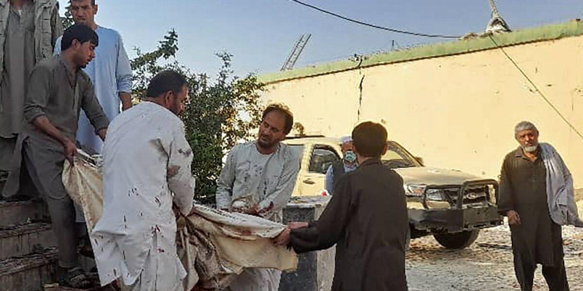 Afghan men carry the dead body of a victim to an ambulance after a bomb attack at a mosque in Kunduz, Afghanistan, on Oct. 8, 2021. (AFP via Getty Images)