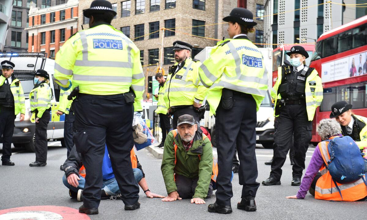 Climate activists from the group Insulate Britain block the road as police officers work to remove and arrest them during a demonstration in central London on Oct. 8, 2021. (Daniel Sorabji/ AFP via Getty Images)