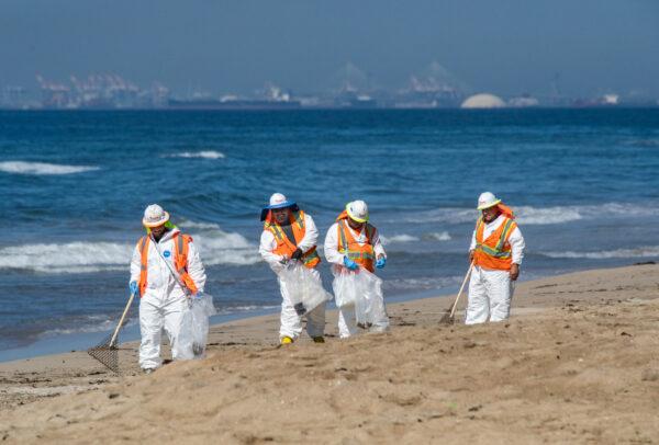 Workers clean an oil spill along the coastline in Huntington Beach, Calif., on Oct. 5, 2021. (John Fredricks/The Epoch Times)