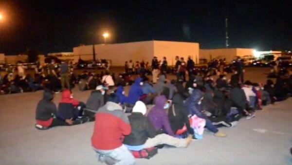 Migrants sit on the ground after they were taken out of trucks by immigration authorities, in Ciudad Victoria, Tamaulipas, Mexico, on Oct. 8, 2021. (Tamaulipas Public Safety Secretariat Handout via AP/Screenshot via NTD)