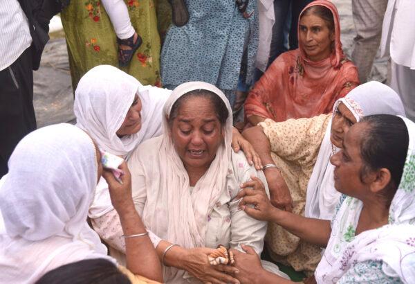 Relatives and neighbors of a farmer who was killed Oct. 3, 2021, after being run over by a car owned by India's junior home minister mourn at Tikonia village in Lakhimpur Kheri, Uttar Pradesh state, India, on Oct. 4, 2021. (AP Photo)