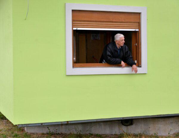 Vojin Kusic's stands on window of his rotating house in a town of Srbac, northern Bosnia, on Oct. 10, 2021. (Radivoje Pavicic/AP Photo)