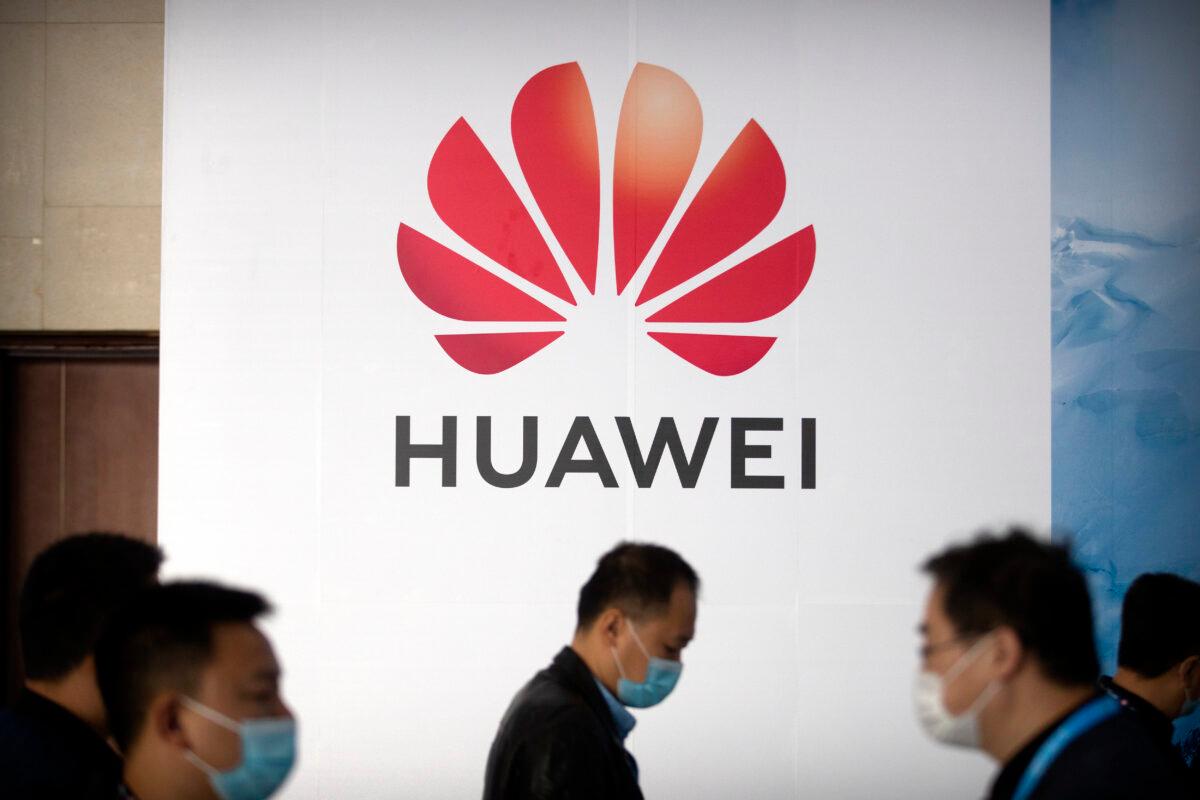 People walk past a billboard advertising Chinese tech company Huawei at the PT Expo in Beijing, China, on Oct. 14, 2020. (Mark Schiefelbein/AP Photo)