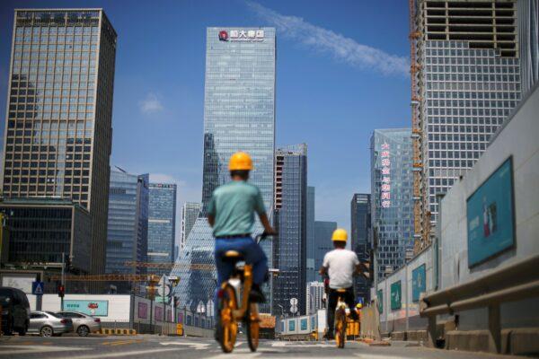 Men ride bicycles past construction sites near the headquarters of China's Evergrande Group in Shenzhen, Guangdong Province, China, on Sept. 26, 2021. (Aly Song/Reuters)