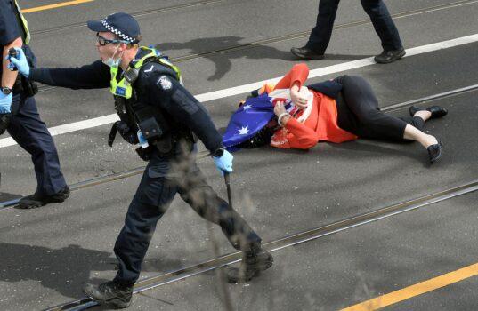 A protester is pushed to the ground by the police during an anti-lockdown rally in Melbourne, Australia, on Sept. 18, 2021. (William West/AFP via Getty Images)
