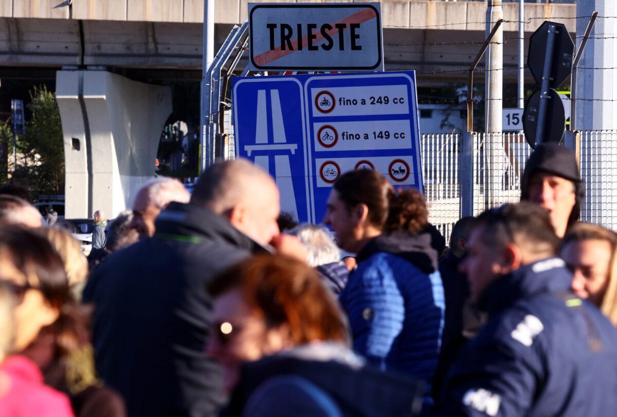 Port workers gather outside the entrance of the major port of Trieste to protest against the implementation of the COVID-19 health pass, the Green Pass, in the workplace, in Trieste, Italy, on Oct. 15, 2021. (Borut Zivulovic/Reuters)