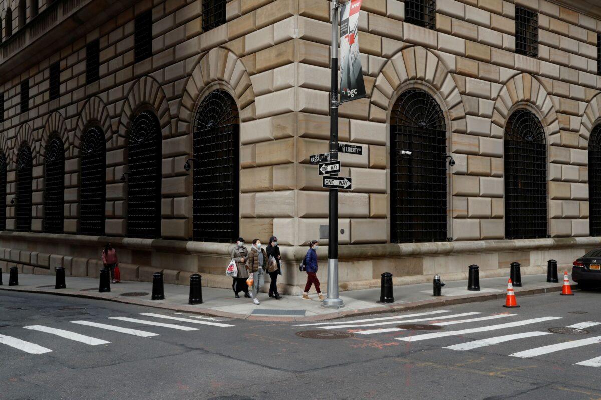 People walk wearing masks outside the Federal Reserve Bank of New York in New York City on March 18, 2020. (Lucas Jackson/Reuters)