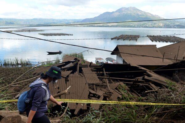 A woman walks past houses by Lake Batur which were damaged by an earthquake-triggered landslide in Bangli, on the island of Bali, Indonesia on Oct. 16, 2021. (Dewa Raka/AP Photo)
