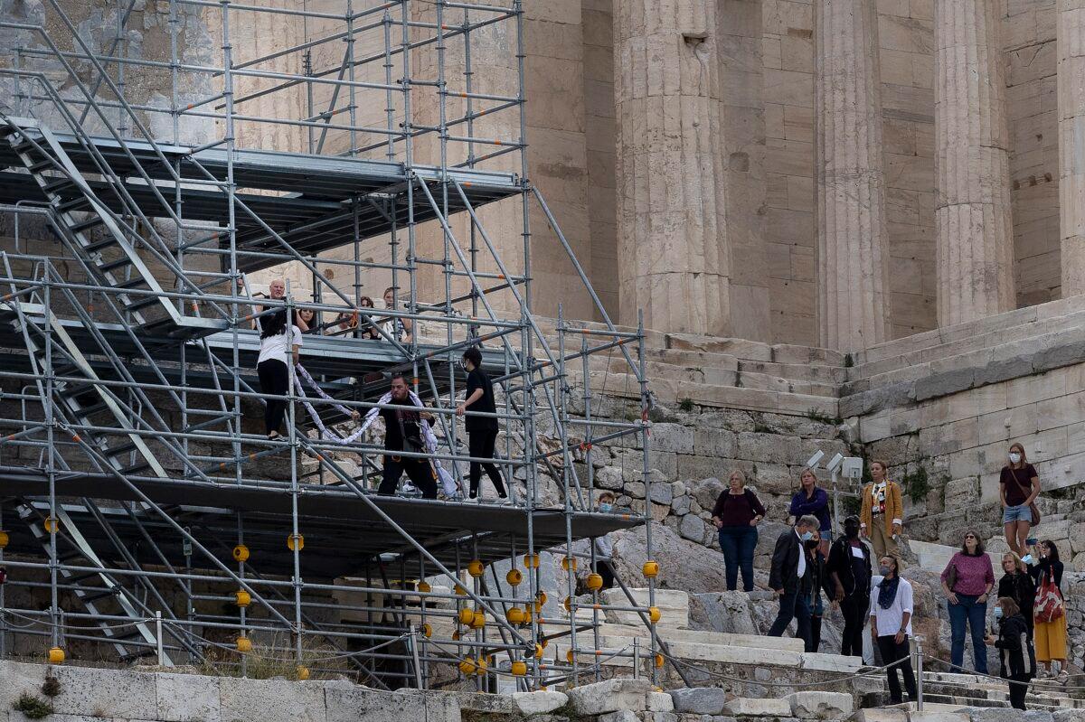 Security staff try to take a banner from protesters on scaffolding at the Acropolis hill, in Athens, Greece, on Oct. 17, 2021. (Yorgos Karahalis/AP Photo)
