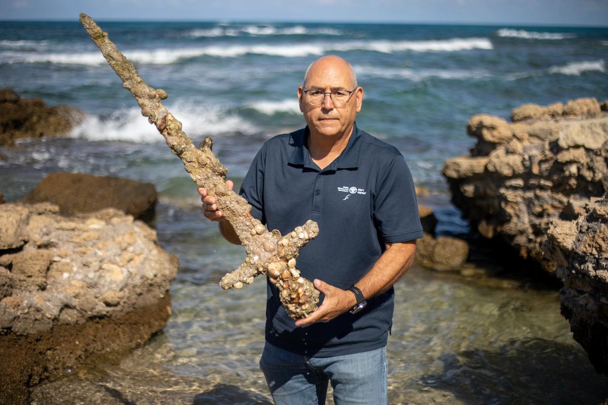 Jacob Sharvit, director of the Marine Archaeology Unit of the Israel Antiquities Authority holds a yard-long sword, that experts say dates back to the Crusaders, in the Mediterranean seaport of Cesarea, Israel, on Oct. 19, 2021. (Ariel Schalit/AP Photo)