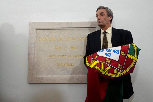 Alvaro de Sousa Mendes holds the Portuguese flag presented to him next to the plaque honoring his grandfather, Aristides de Sousa Mendes, at the National Pantheon in Lisbon, Portugal, on Oct. 19, 2021. (Armando Franca/AP Photo)