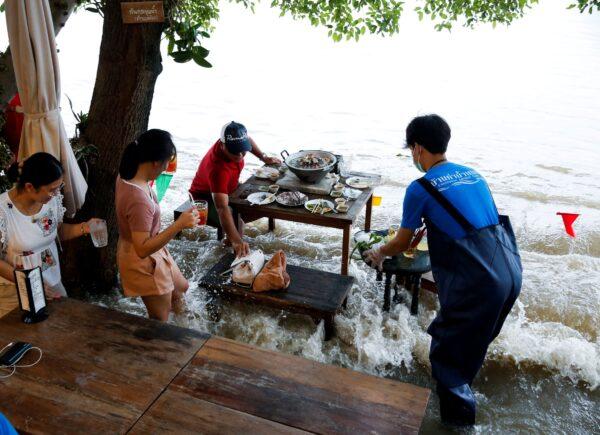 Patrons stand up from their tables every time the waves come in, on a riverbank in Nonthaburi near Bangkok, Thailand, on Oct. 7, 2021. (Soe Zeya Tun/Reuters)
