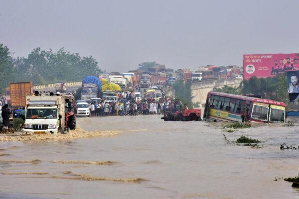 Commuters stand on a flyover on a flooded national highway after river Kosi overflowed following heavy rains near Rampur in India's Uttar Pradesh state on Oct. 20, 2021. (AFP via Getty Images)