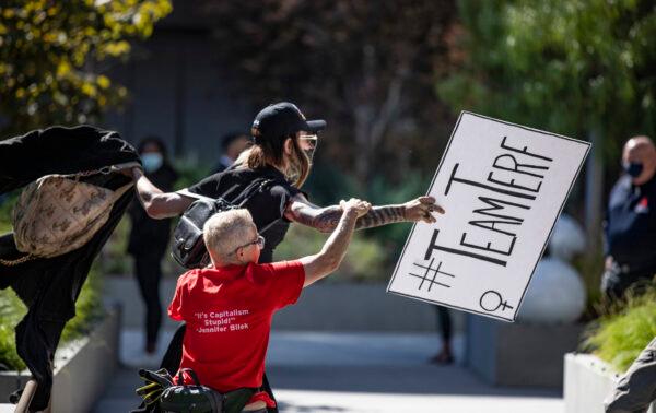 Counter protestor Joey Brite chases after an individual who stole one of her group's signs as protestors and counter-protestors voicing for or against a popular Dave Chapelle comedy special currently airing on Netflix gather in front of Netflix's Vine Street offices in Los Angeles on Oct. 20, 2021. (John Fredricks/The Epoch Times)