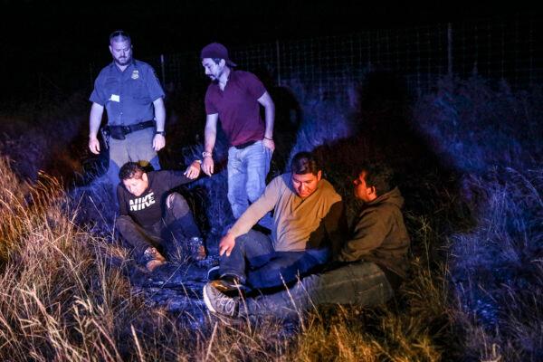 A Border Patrol agent picks up four illegal aliens after Kinney County Sheriffs deputies arrested a U.S. citizen smuggler who was transporting them to San Antonio, in Kinney County, Texas, on Oct. 20, 2021. (Charlotte Cuthbertson/The Epoch Times)