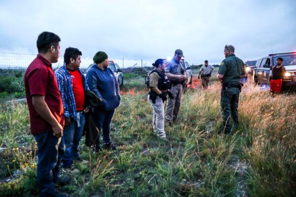 A Border Patrol agent picks up three illegal aliens after Texas state troopers arrested two U.S. citizen smugglers who were transporting them to San Antonio, in Kinney County, Texas, on Oct. 20, 2021. (Charlotte Cuthbertson/The Epoch Times)